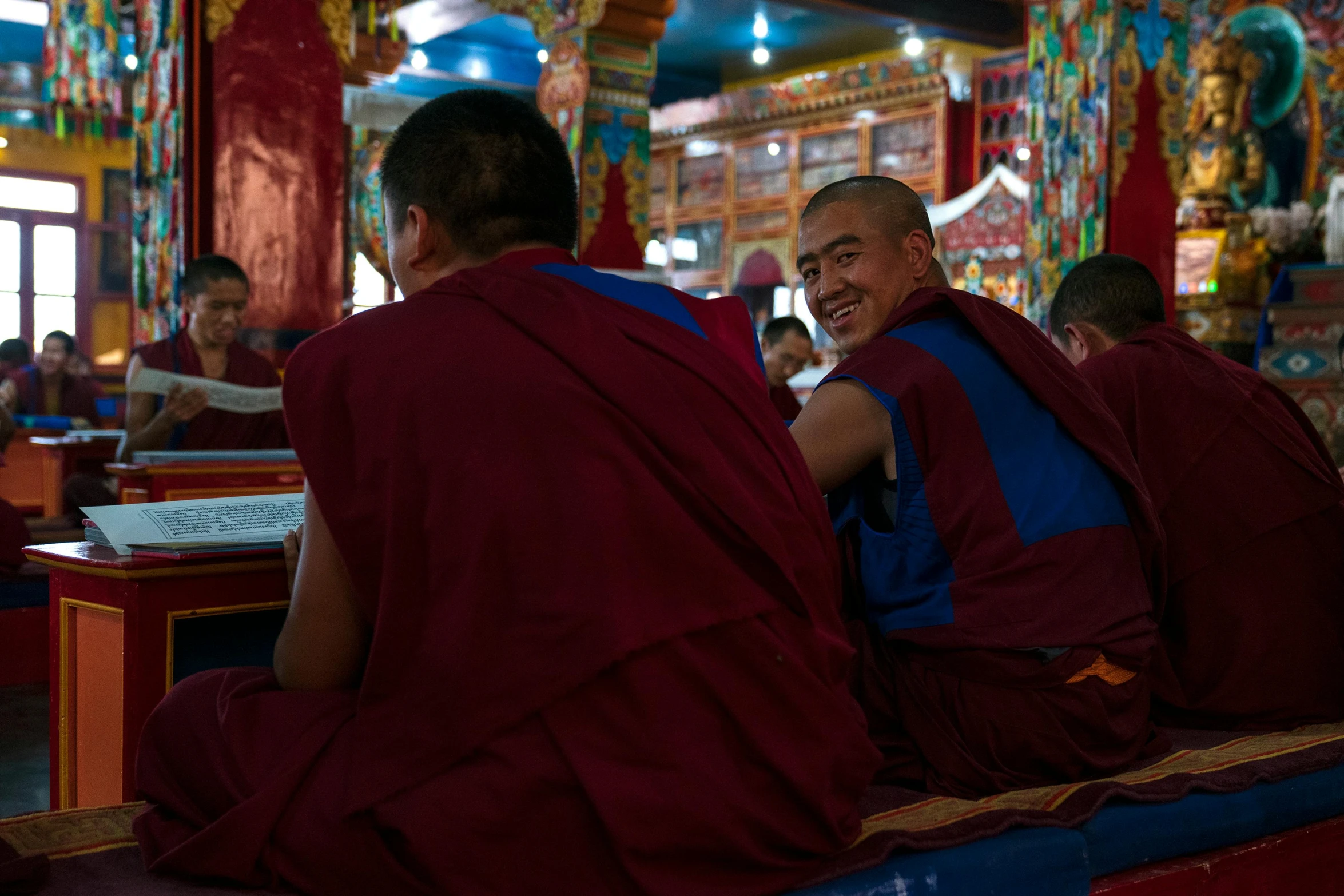 a couple of men sitting next to each other in a room, hurufiyya, monk clothes, red and blue garments, lama, avatar image