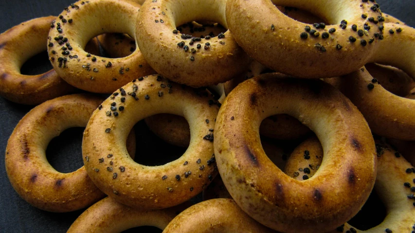 a pile of bagels sitting on top of a table, pexels, hurufiyya, black holes, all enclosed in a circle, middle eastern, thumbnail