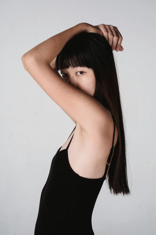 a woman in a black dress posing for a picture, an album cover, inspired by Wang E, pexels contest winner, hair blackbangs hair, skinny upper arms, artgem lau, 2 4 year old female model