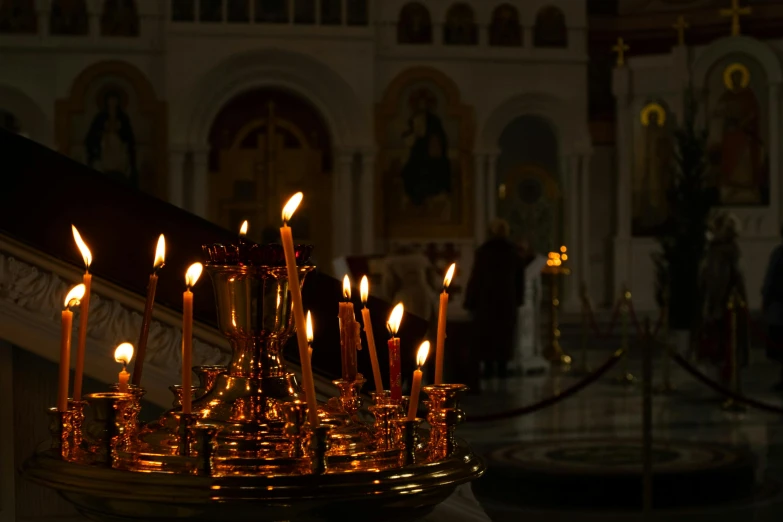a bunch of candles are lit in a church, by Attila Meszlenyi, pexels, greek, copper and brass, profile image, morning atmosphere