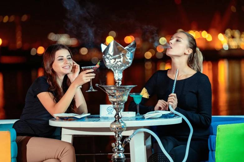 two women sitting at a table smoking a hooket, by Julia Pishtar, shutterstock, hurufiyya, cocktail bar, blue, arabian features, at the waterside