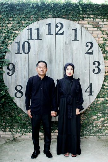 a man and a woman standing in front of a clock, a picture, inspired by Bernardino Mei, hurufiyya, 2019 trending photo, couple portrait, black habit, modest!