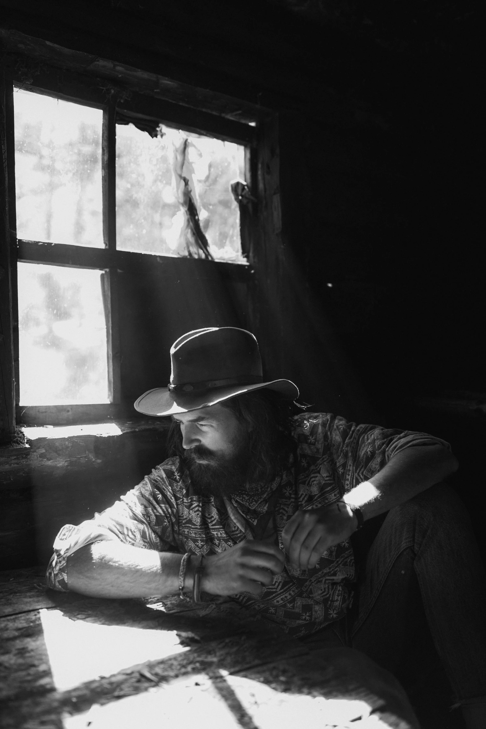 a black and white photo of a man wearing a hat, by Brian 'Chippy' Dugan, light inside the hut, jesse mccree, square, brian wilson