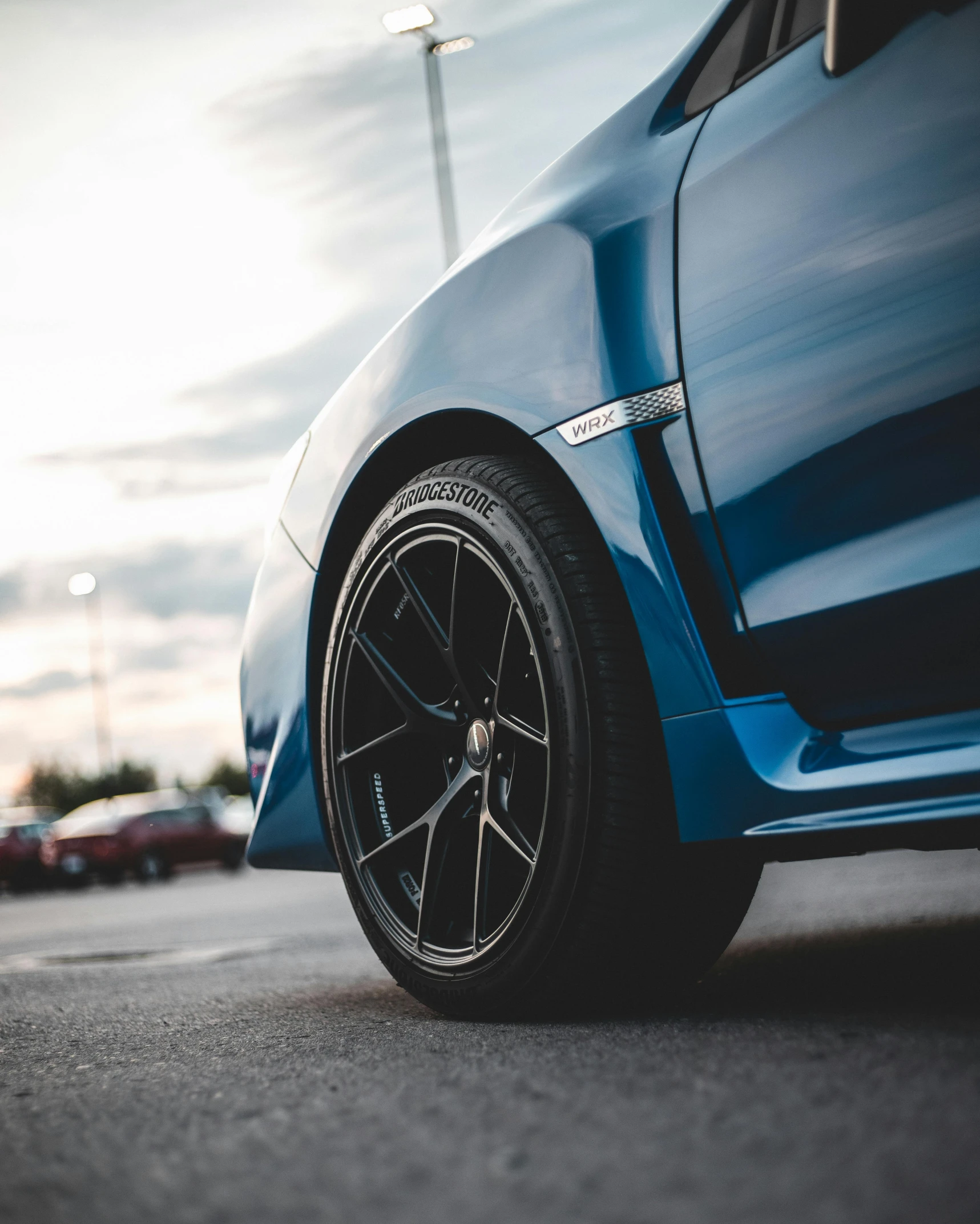 a blue car parked in a parking lot, black rims, zoomed in, thumbnail, colour corrected