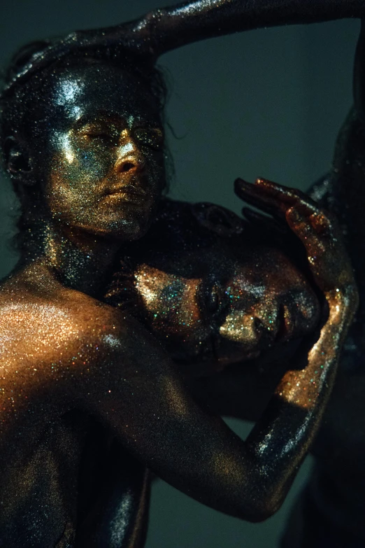 a close up of a statue of a person holding a ball, an album cover, inspired by Elsa Bleda, art photography, gold bodypaint, glitter gif, lesbians, body painted with black fluid