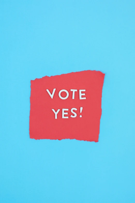 a red piece of paper with the words vote yes written on it, an album cover, with a blue background, ( ( mads berg ) ), overhead shot, promo image