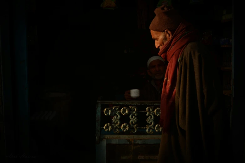 a man that is standing in the dark, by Eglon van der Neer, unsplash contest winner, hyperrealism, tibet, next to a cup, in a monestry natural lighting, winter sun