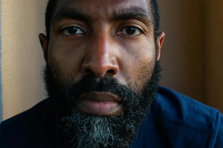 a close up of a man with a beard, an album cover, inspired by Gordon Parks, unsplash, hyperrealism, 40 years old women, ray lewis, looking straight to camera, a high angle shot