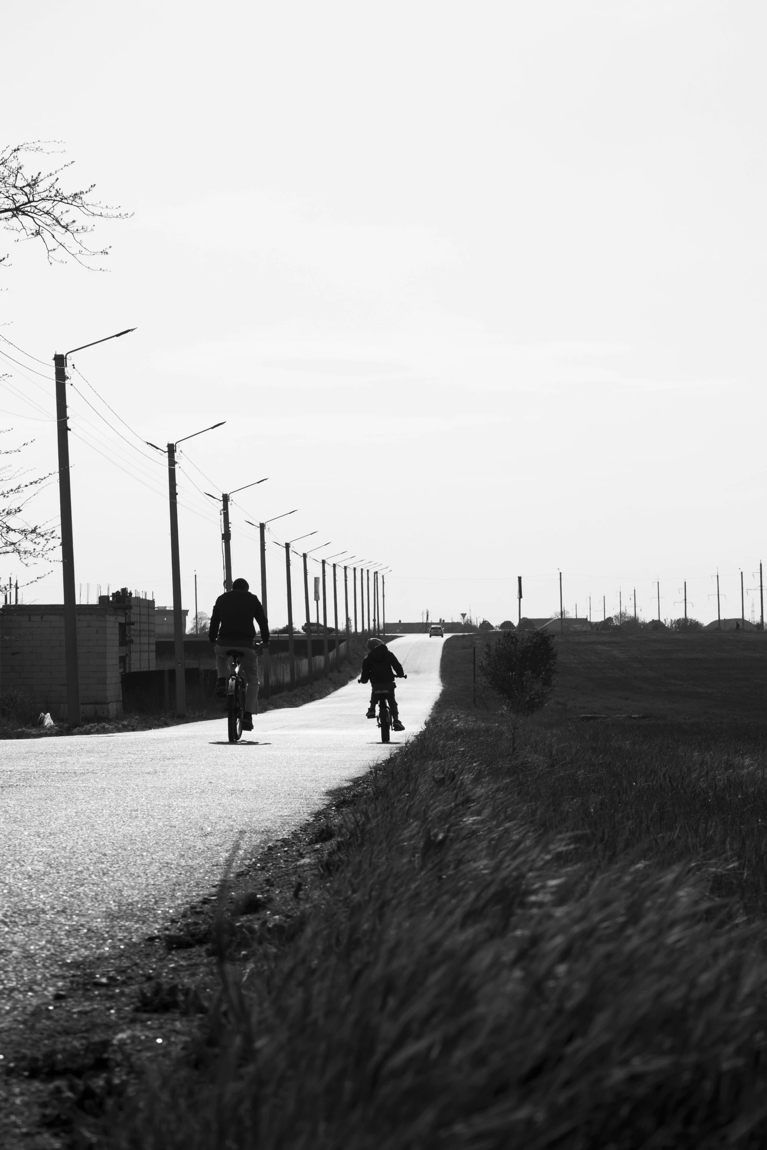 a black and white photo of a person on a skateboard, a black and white photo, by Jacob Toorenvliet, conceptual art, roads among fields, powerlines, cycling!!, low quality photograph