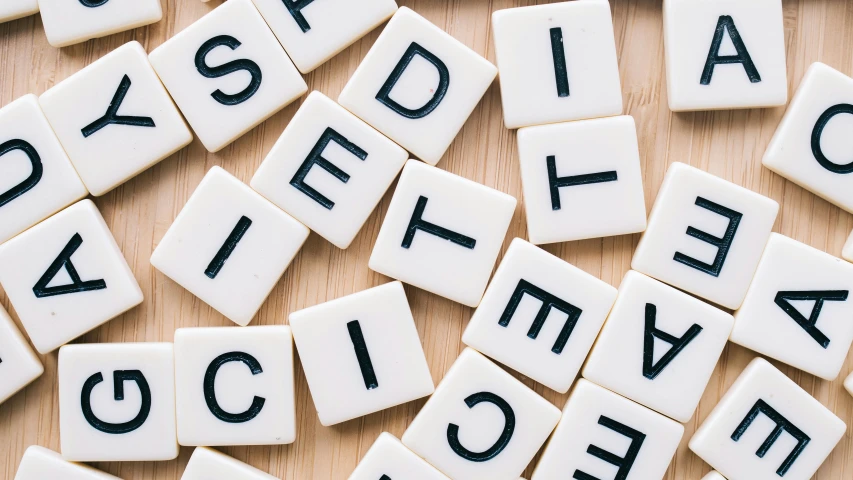 a pile of scrabbles sitting on top of a wooden table, by Jessie Algie, trending on pexels, letterism, letter s, sci-fy, on a pale background, secret <