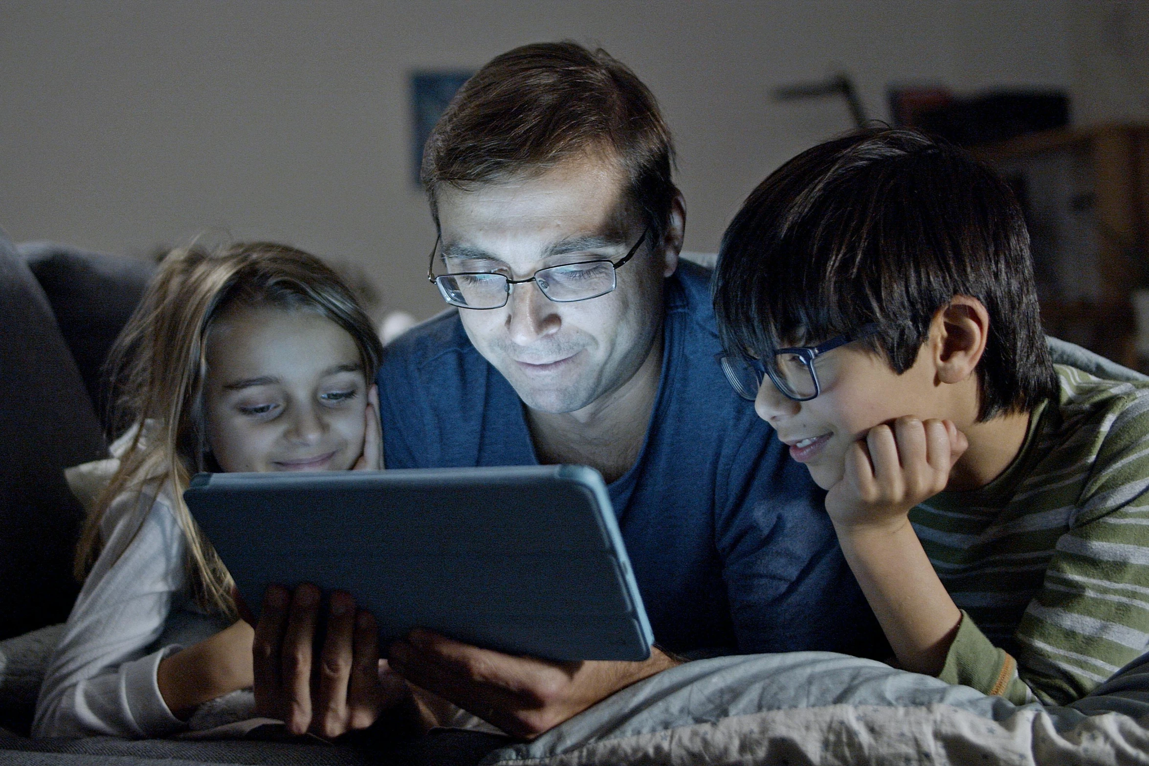 a man and two children looking at a tablet, a digital rendering, pexels, night time footage, still image from tv series, instagram post, nerd