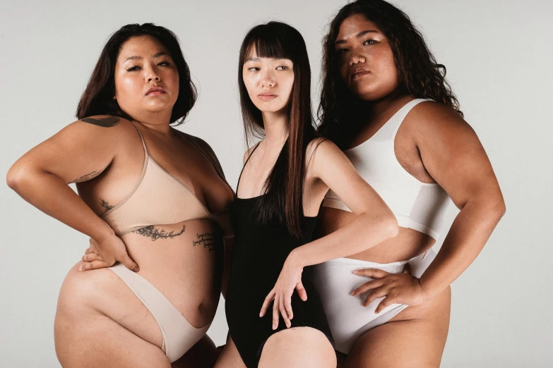 a group of three women standing next to each other, inspired by Vanessa Beecroft, trending on pexels, big stomach, half asian, wearing leotard, skincare