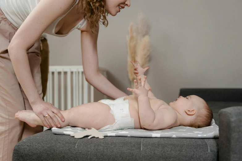 a woman standing over a baby in a diaper, by Emma Andijewska, pexels contest winner, incoherents, she is laying on her back, gif, low quality photo, scientific photo