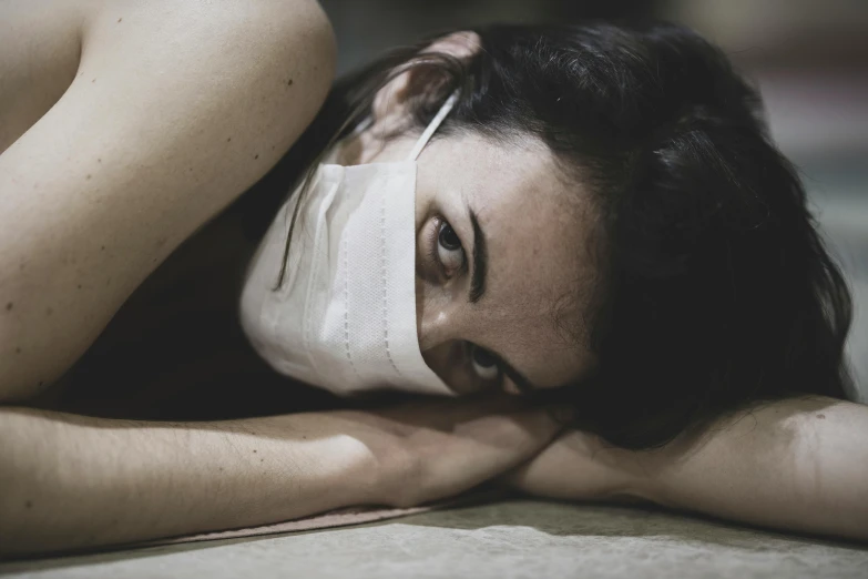 a woman laying on the floor wearing a face mask, a photo, pexels contest winner, hyperrealism, bandage, blank stare”, nursing, experimental