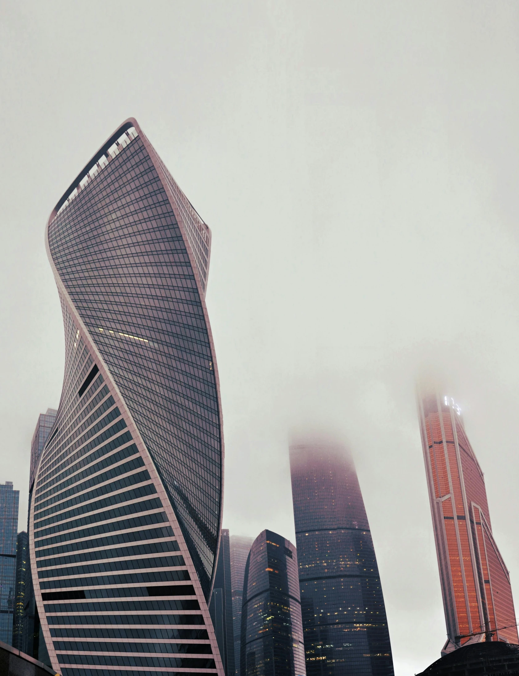 a very tall building sitting in the middle of a city, inspired by Zaha Hadid, pexels contest winner, russia, misty weather, promo image, swirled architecture