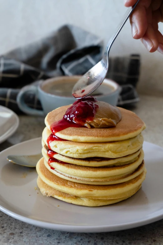 a stack of pancakes sitting on top of a white plate, inspired by Richmond Barthé, unsplash, spoon placed, pouring, jelly, in australia