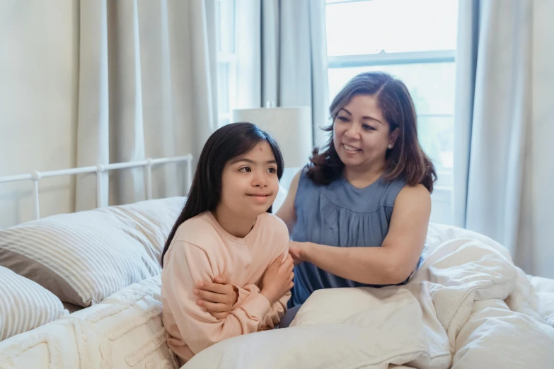 a woman sitting on top of a bed next to a little girl, inspired by Ruth Jên, pexels contest winner, supportive, avatar image, asian descent, teenage girl