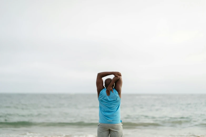 a man standing on top of a beach next to the ocean, a portrait, by Charles Ellison, unsplash, back arched, stretch, plain background, 40 years old women