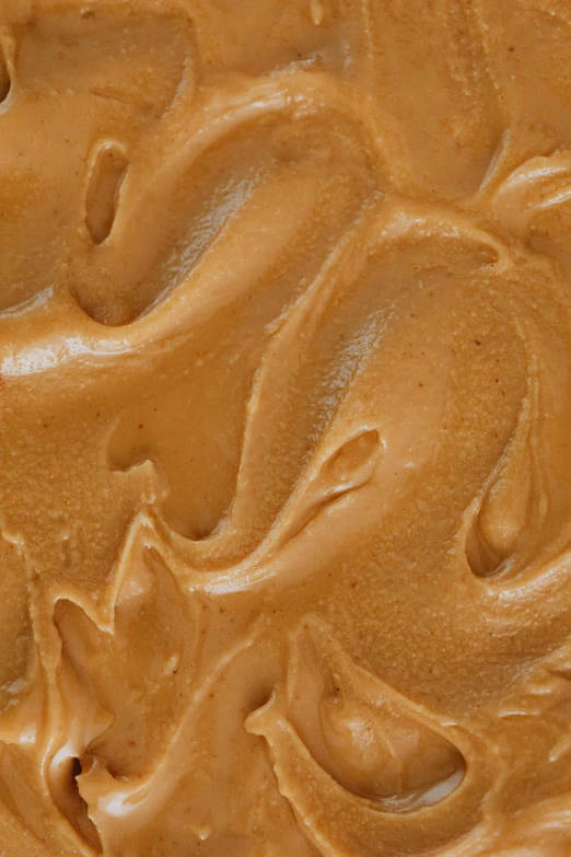 a close up of a cake with chocolate frosting, cinnamon #b57e59 skin color, liquid translucent amber, peanuts, deeply hyperdetailed