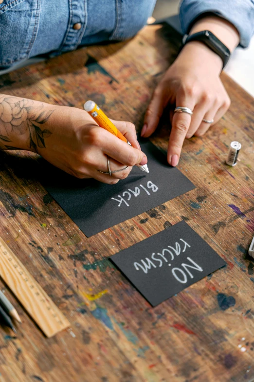 a person sitting at a table writing on a piece of paper, arbeitsrat für kunst, paint on black velvet canvas, labels, handcrafted, thumbnail