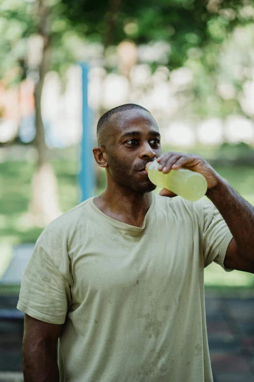 a man standing in a park with a frisbee in his mouth, by Andrew Stevovich, pexels contest winner, renaissance, moringa juice, wearing yellow croptop, kara walker james jean, holding a drink