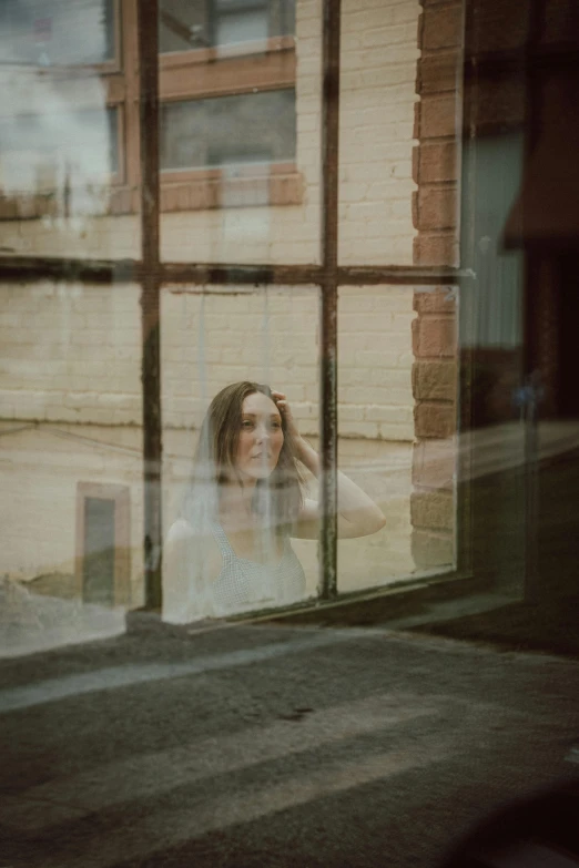 a woman standing in front of a window talking on a cell phone, a picture, inspired by Elsa Bleda, pexels contest winner, person made out of glass, handsome girl, in front of a garage, floating away