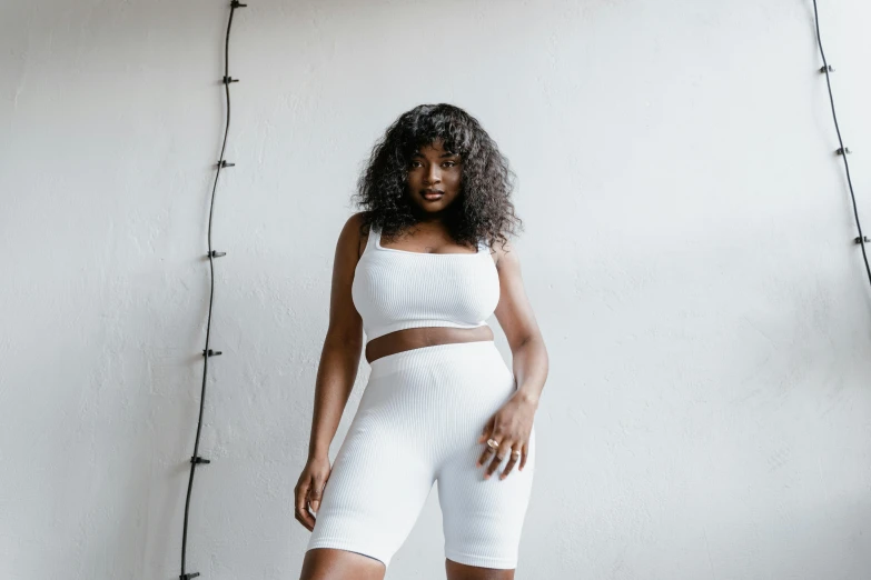 a woman in a white top and shorts posing for a picture, inspired by Esaias Boursse, trending on pexels, shaquille o'neil pregnant, wearing tight suit, nettie wakefield, white leggings