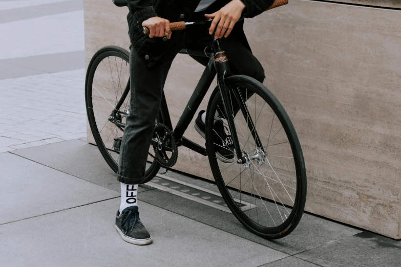 a man sitting on a bike leaning against a wall, pexels contest winner, gray shorts and black socks, background image, federation clothing, wearing a black jacket