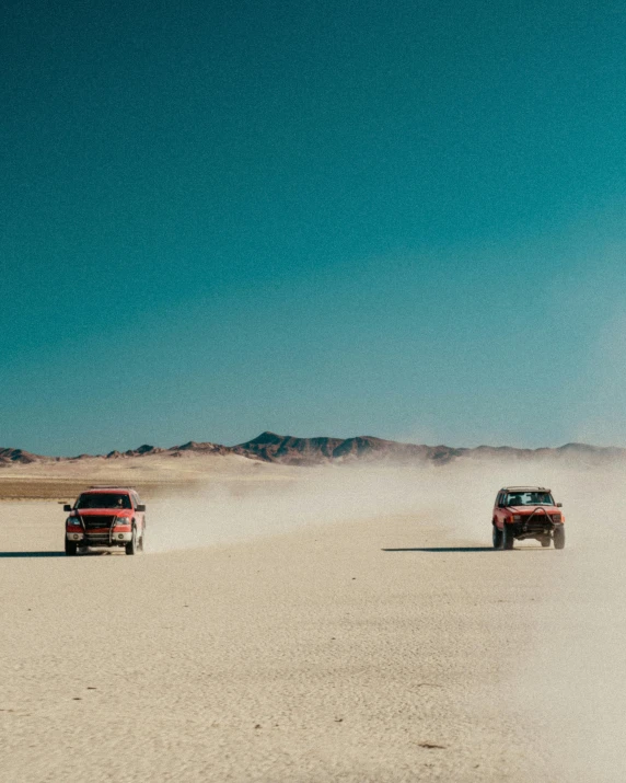 a couple of trucks driving down a dirt road, unsplash contest winner, minimalism, fear and loathing in las vegas, racing, intimidating floating sand, vintage cars
