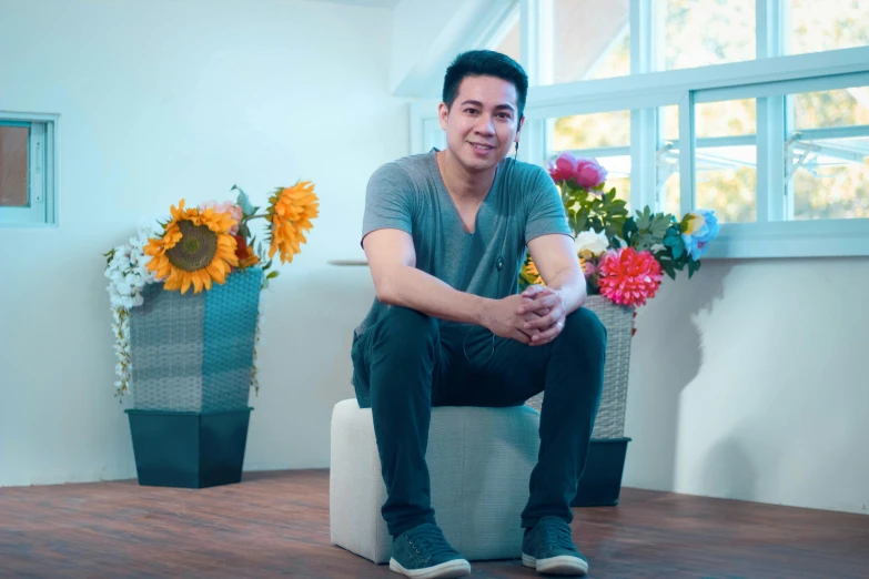 a man sitting on a stool next to a vase of flowers, damien tran, avatar image, profile image, indoor picture