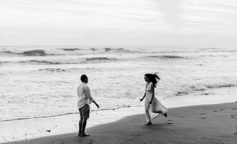 a black and white photo of two people walking on the beach, a black and white photo, unsplash, man proposing his girlfriend, running freely, actors, playing