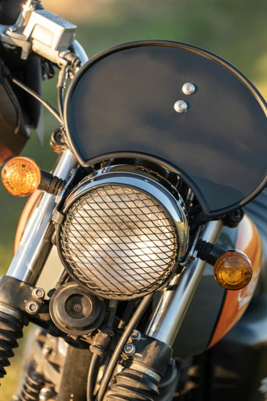 a close up of the front of a motorcycle, by Bernie D’Andrea, unsplash, photorealism, round headlights, featuring rhodium wires, brown, sun lighting