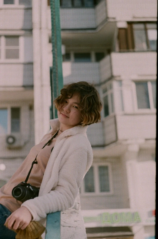 a woman sitting on a post with a camera, inspired by Elsa Bleda, happening, wavy short hair, over his shoulder, slightly smiling, lo fi