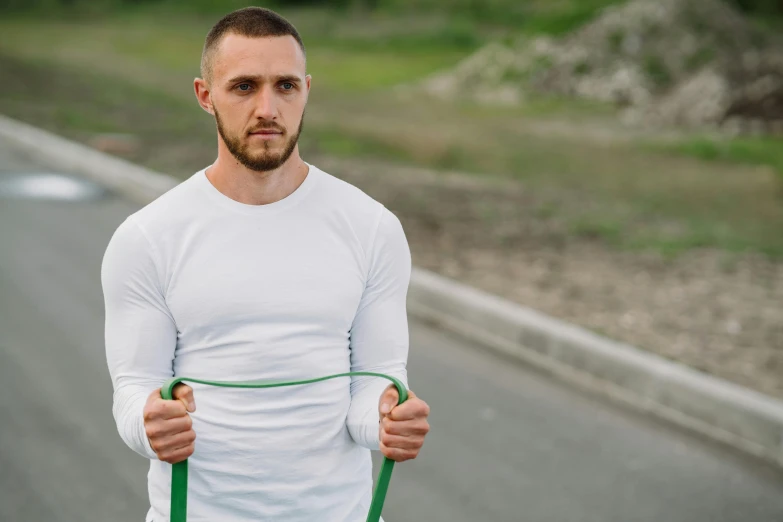 a man standing on the side of a road holding a green rope, wearing a muscle tee shirt, avatar image, white sleeves, background image