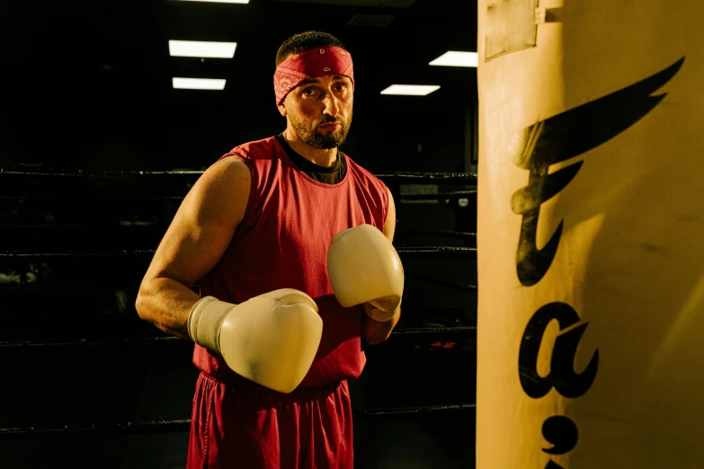 a man standing next to a punching bag, a portrait, by Lisa Milroy, pexels contest winner, [ theatrical ], sam hyde, white bandages on fists, profile image
