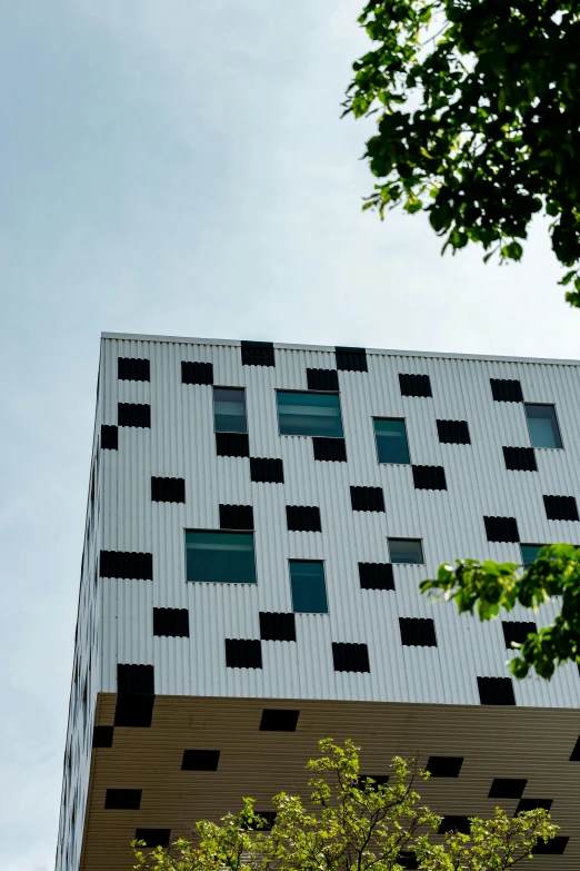 a clock on a pole in front of a building, an album cover, inspired by Bauhaus, unsplash, bengal school of art, perforated metal, view from below, cube, white with black spots