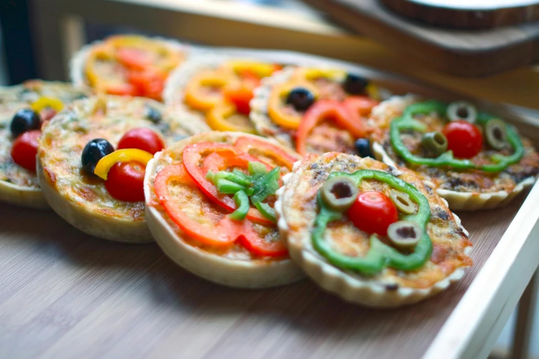 a close up of a tray of food on a table, inspired by Géza Dósa, unsplash, one tomato slice, pastry lizard, multicoloured, in a row