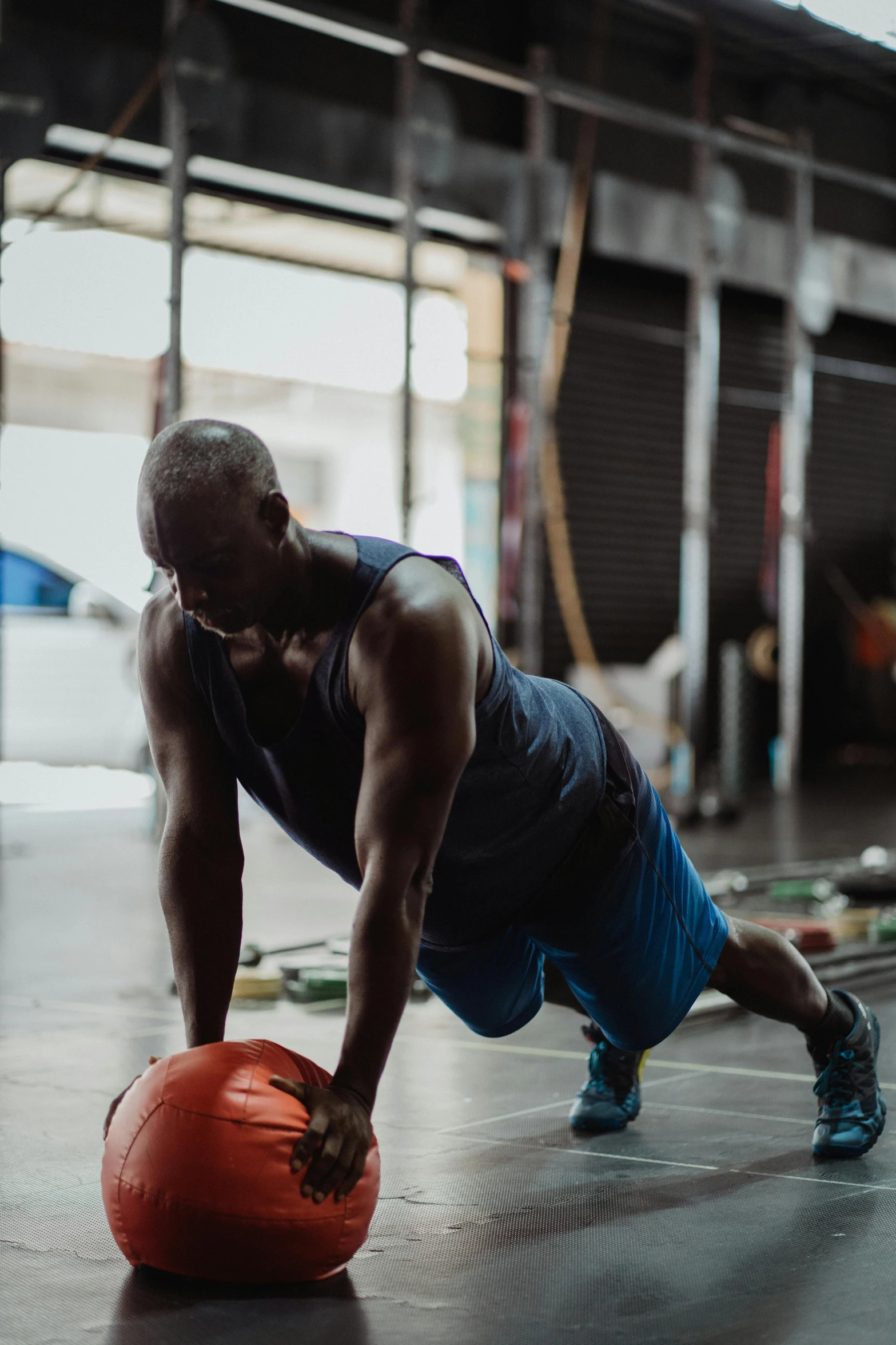 a man doing push ups on an orange ball, by Jessie Algie, atiba jefferson, in a gym, profile image, lachlan bailey