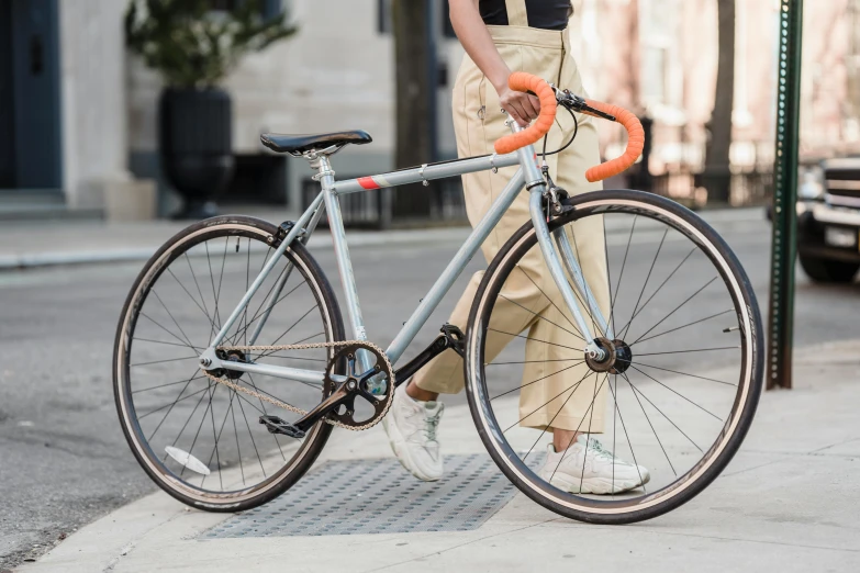 a woman standing next to a bike on a city street, pexels contest winner, flat grey color, speedster, grey orange, legs visible