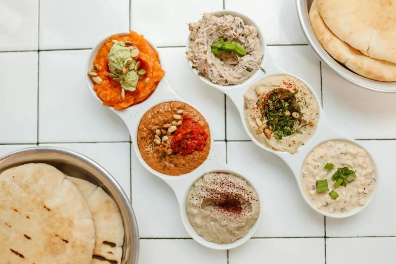 a table topped with bowls of different types of food, a mosaic, by Will Ellis, trending on unsplash, dau-al-set, humus, creamy skin, israel, background image