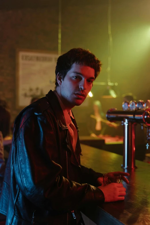 a man in a leather jacket sitting at a bar, inspired by Nan Goldin, cobra, finn wolfhard, still from riverdale, getty images, romance