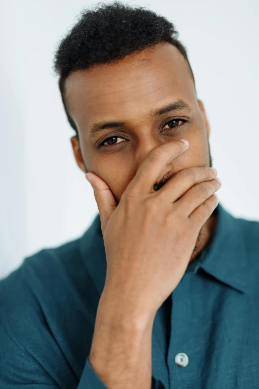 a close up of a person with a hand on his face, inspired by Ismail Gulgee, in a dark teal polo shirt, androgynous person, embarrassed, receding hairline