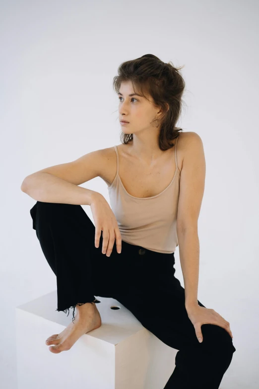 a woman sitting on top of a white box, wearing black camisole outfit, natural muted tones, wearing pants and a t-shirt, zac retz