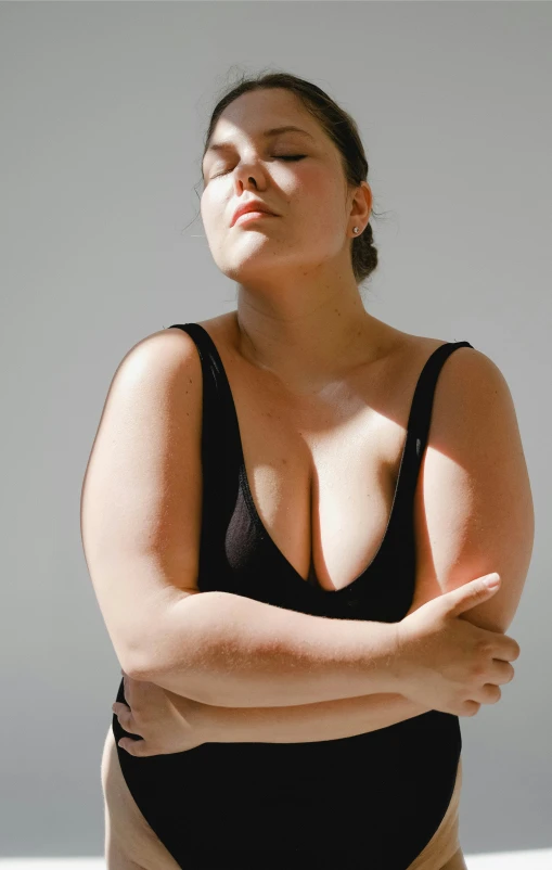 a woman in a black swimsuit posing for a picture, an album cover, unsplash, double chin, sunlit, bloated, high quality photo