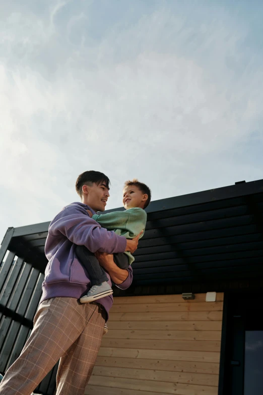 a man holding a child in his arms, unsplash, visual art, shed roof, non-binary, teenage boy, slide show