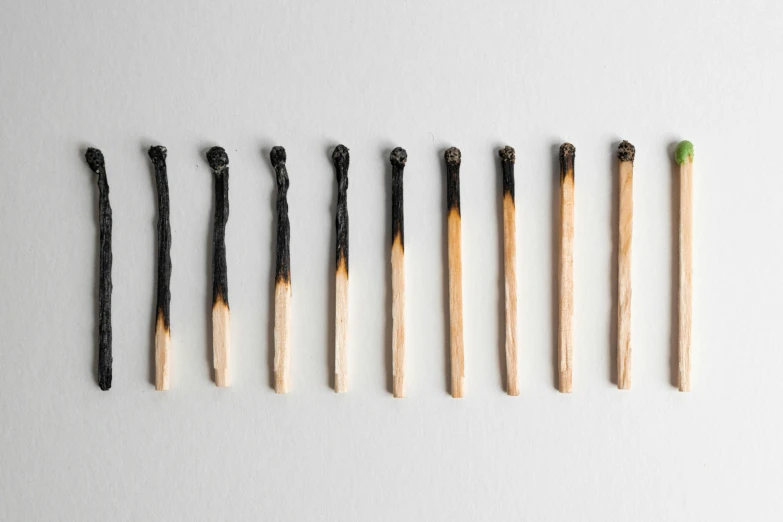 a row of matches sitting next to each other, inspired by Rodney Joseph Burn, auto-destructive art, on a pale background, charred, trending on dezeen, group of seven