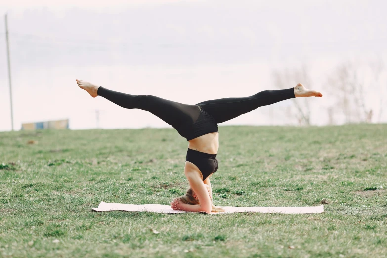 a woman doing a handstand in a field, unsplash, arabesque, avatar image, marjaryasana and bitilasana, sydney park, hovering indecision