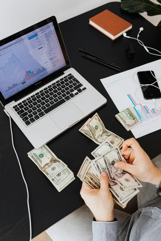 a person sitting at a desk with a laptop and money, pexels contest winner, 🚀🌈🤩, low iso, corrupted data, loosely cropped