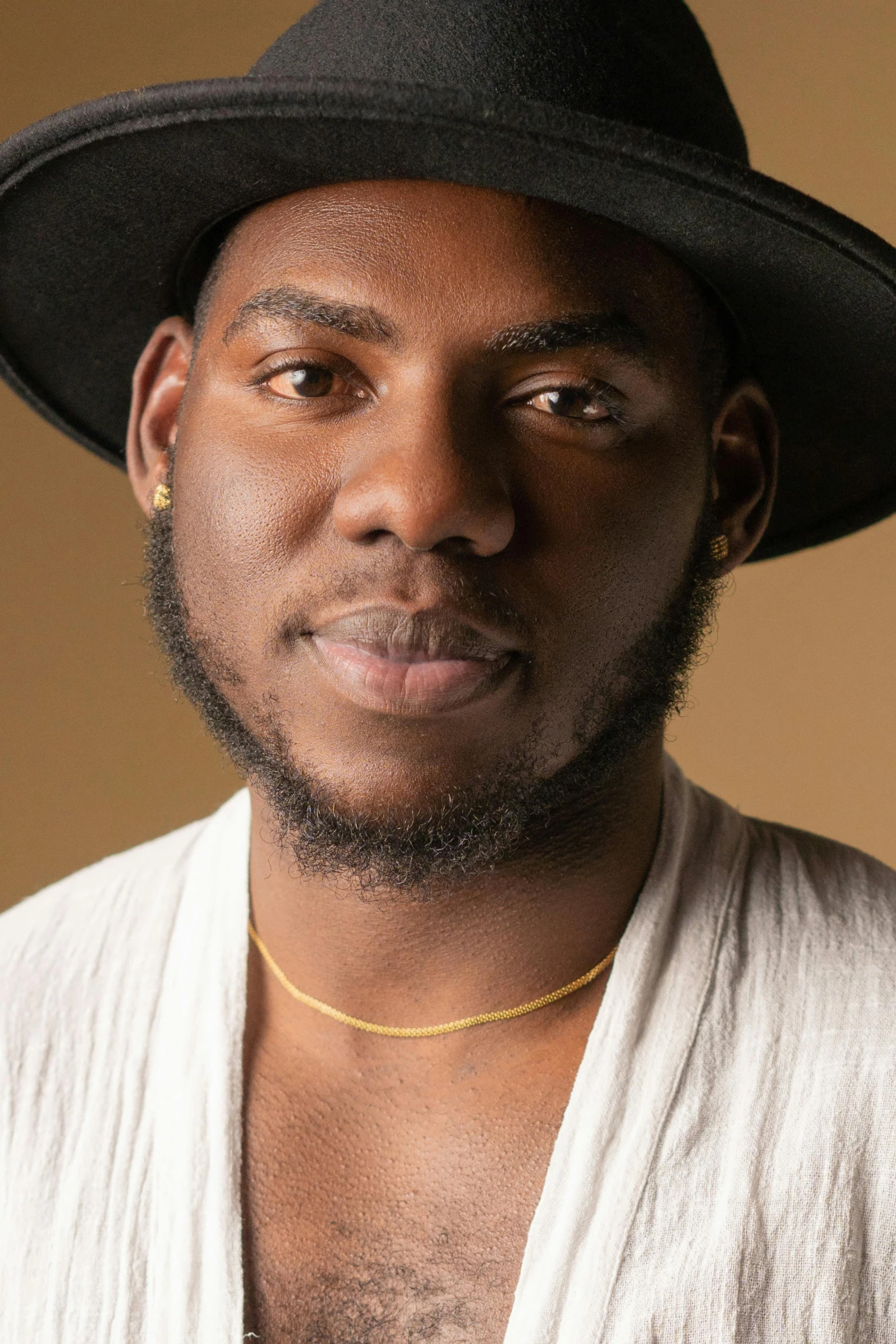 a close up of a person wearing a hat, black arts movement, extremely handsome, ashy, brown, plain background