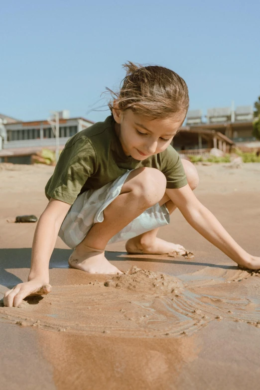 a little girl playing in the sand on the beach, by Elizabeth Durack, pexels contest winner, visual art, girl with warship parts, wet clay, a handsome, brown